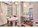 Elegant bathroom with pedestal sink, herringbone floors, and large mirror at 7000 S Sheridan Blvd, Littleton, CO 80128