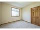 Bright bedroom with carpeted floor, large window, and a door at 2203 S County Road 185, Byers, CO 80103
