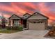 Two-story house with stone and beige siding, two-car garage, and landscaped yard at 10303 Pitkin Ct, Commerce City, CO 80022