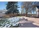Backyard with concrete patio, mature trees, and partial snow cover at 640 Pacific Ave, Fort Lupton, CO 80621