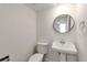 Modern powder room featuring pedestal sink and round mirror at 824 W Geddes Cir, Littleton, CO 80120