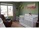 Bedroom with crib, armchair, and view of backyard at 5411 E Courtney Ave, Castle Rock, CO 80104