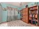 Bedroom with teal walls, built-in bookcase, and large window with curtains at 12366 Jasmine Pl, Brighton, CO 80602