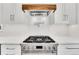 Modern gas range with a wood vent hood and white subway tile backsplash at 975 S Fillmore Way, Denver, CO 80209