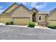 Tan two-story townhome with two-car garage, landscaping, and a paved driveway at 6678 S Shawnee Ct, Aurora, CO 80016