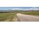 Paved road winding through a grassy field and mountains at 8866 Waterleaf Ln, Littleton, CO 80125