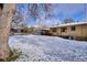 Snowy backyard with patio, mature trees, and a partially visible house at 2765 S Winona Ct, Denver, CO 80236