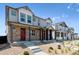 Row of townhomes, each with stone and siding exterior and red door at 9859 Biscay St, Commerce City, CO 80022