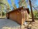 Attached two-car garage with wood siding and a spacious driveway at 8782 S Ault Ln, Morrison, CO 80465