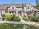 Tan two-story townhome with red door, landscaping, and walkway at 6220 Salvia St, Arvada, CO 80403