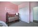 Bedroom featuring a crib, closet, and pink walls at 4079 S Crystal Cir # 201, Aurora, CO 80014