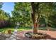 Landscaped backyard with brick patio, mature trees, and lawn at 1575 S Clermont St, Denver, CO 80222