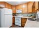 Galley kitchen, white appliances and wood cabinets at 9385 E Center Ave # 1D, Denver, CO 80247