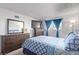 Bright bedroom with dresser, TV, and full bed with blue and white comforter at 381 S Ames St # B103, Lakewood, CO 80226