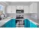 Kitchen features teal and white cabinetry, stainless appliances, and stylish backsplash at 9644 W Cornell Pl, Lakewood, CO 80227