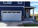 White two-car garage with blue siding and landscaping at 45780 Silverdrop Ave, Bennett, CO 80102