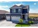 Two-story blue house with white two-car garage and landscaping; view of farmland at 45780 Silverdrop Ave, Bennett, CO 80102