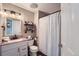 Clean bathroom with a single vanity, shower/tub combo, and rustic shelving at 3944 Morning Glory Dr, Castle Rock, CO 80109