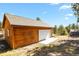 Detached garage with white door and wood siding at 28730 Mountain View Rd, Conifer, CO 80433