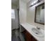 Clean bathroom with single sink vanity, light wood cabinets, and gray wood-look flooring at 4361 Argonne St, Denver, CO 80249