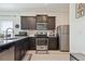 Modern kitchen featuring dark cabinetry, granite countertops, and stainless steel appliances at 7418 Blue River Ave, Frederick, CO 80530