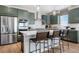 The kitchen offers stainless steel appliances, an island with bar seating, and green cabinets at 16594 W 93Rd Way, Arvada, CO 80007