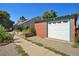 Detached brick garage with white door and adjacent garden at 1843 Spruce St, Boulder, CO 80302