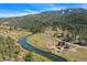 Aerial view of home nestled along a river with mountain backdrop at 2677 S Platte River Rd, Sedalia, CO 80135