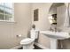 Powder room with a pedestal sink, round mirror, and decorative wallpaper at 2627 Hillcroft Ln, Castle Rock, CO 80104