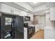 Modern kitchen with white cabinets, black appliances, and gray tile backsplash at 590 N Logan St # 210, Denver, CO 80203