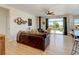 Bright living room with hardwood floors, a leather couch, and a view of the backyard through sliding glass doors at 10691 County Road 23, Fort Lupton, CO 80621