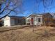 Gray house with red door, attached garage, and mature trees in front at 1103 Stage Dr, Fort Lupton, CO 80621
