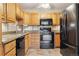 Updated kitchen with black appliances, granite countertops, and oak cabinetry at 585 S Alton Way # 4D, Denver, CO 80247