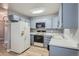 Galley kitchen with light blue cabinetry and white appliances at 3164 S Wheeling Way # 308, Aurora, CO 80014