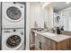 Modern bathroom with stackable washer and dryer, vanity with grey countertop, and a large mirror at 3575 Chestnut Pl # 605, Denver, CO 80216