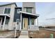 Two-story modern home with gray and blue siding, white porch, and yellow front door at 6578 N Nepal Ct, Aurora, CO 80019