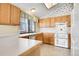 L-shaped kitchen with wood cabinets, white appliances, and tile floor at 10475 W 82Nd Pl, Arvada, CO 80005