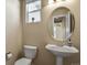 Half-bathroom with a pedestal sink, round mirror, and toilet at 315 Venison Creek Dr, Monument, CO 80132