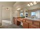 Main bathroom with double vanity, wood cabinetry, and a view into the main bedroom at 315 Venison Creek Dr, Monument, CO 80132