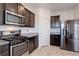 Modern kitchen with dark cabinets, granite counters, and stainless steel appliances at 341 Maple St, Bennett, CO 80102