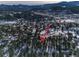 An aerial perspective of homes surrounded by snow-covered pine trees at 30232 Hilltop Dr, Evergreen, CO 80439