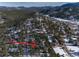 Aerial view of a neighborhood nestled in a snowy, mountainous landscape at 30232 Hilltop Dr, Evergreen, CO 80439