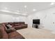 Finished basement with a comfortable sectional sofa and a large TV at 8715 E Iliff Dr, Denver, CO 80231