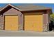 Two-car garage with two yellow doors and stone accents at 8547 Gold Peak Dr # G, Highlands Ranch, CO 80130