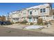 Row of beige townhouses with blue doors, parking and snowy landscaping at 5888 Biscay St # D, Denver, CO 80249