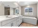 Elegant bathroom with double vanity, soaking tub, and a large mirror at 16591 W 93Rd Ave, Arvada, CO 80007