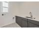 Laundry room with gray cabinets and patterned tile floor at 11077 Star Fall St, Littleton, CO 80125