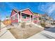 Red single-story home with a front porch, landscaped yard, and sidewalk at 748 Country Road Trl, Berthoud, CO 80513