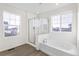 Modern bathroom with a glass shower, soaking tub, and wood-look floor at 1562 Farmstead St, Brighton, CO 80601