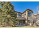 Back exterior showcasing a patio, large windows, and stonework at 7818 Vallagio Ln, Englewood, CO 80112
